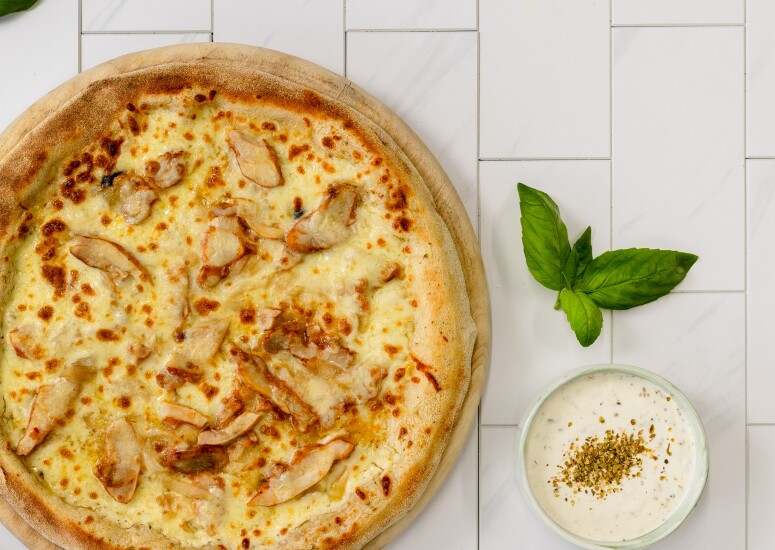 Pizza L'orientale ISI, base crème : mozzarella, émincés de poulet marinés aux épices, oignons frits, sauce blanche, origan
